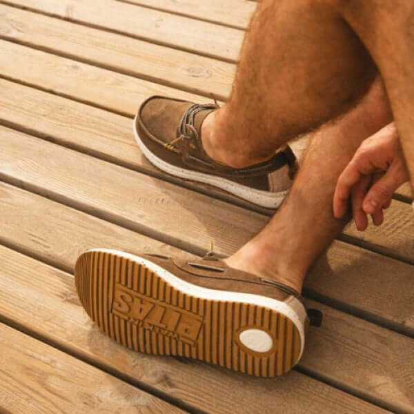 Man wearing Byron ultralight boat shoes with rubber outsole while sitting on wooden deck.